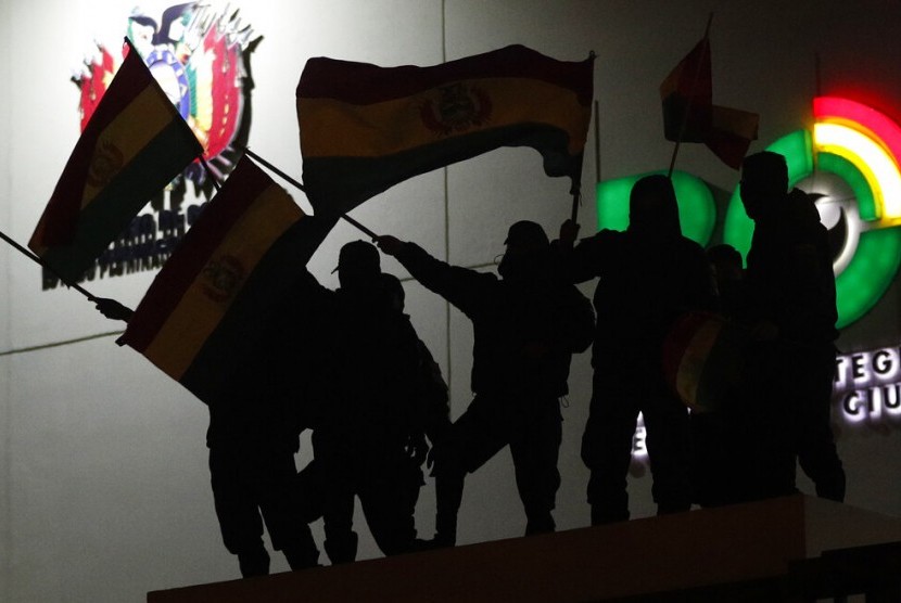 Polisi Bolivia mengibarkan bendera Bolivia dari atas atap kantor polisi di La Paz, Bolivia, Sabtu (9/11).