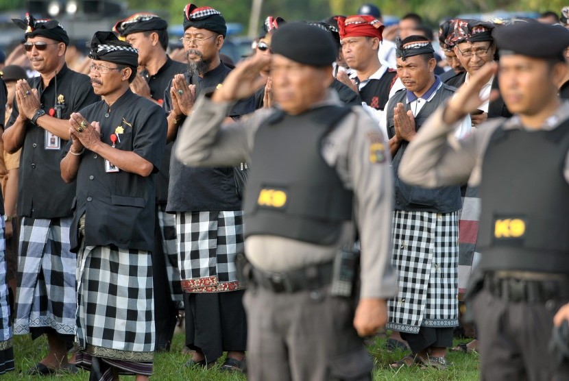 Polisi dan anggota satuan pengamanan adat atau Pecalang memberi penghormatan saat apel kesiagaan pasukan Operasi Lilin 2015 di Lapangan Puputan Margarana, Denpasar, Rabu (23/12).