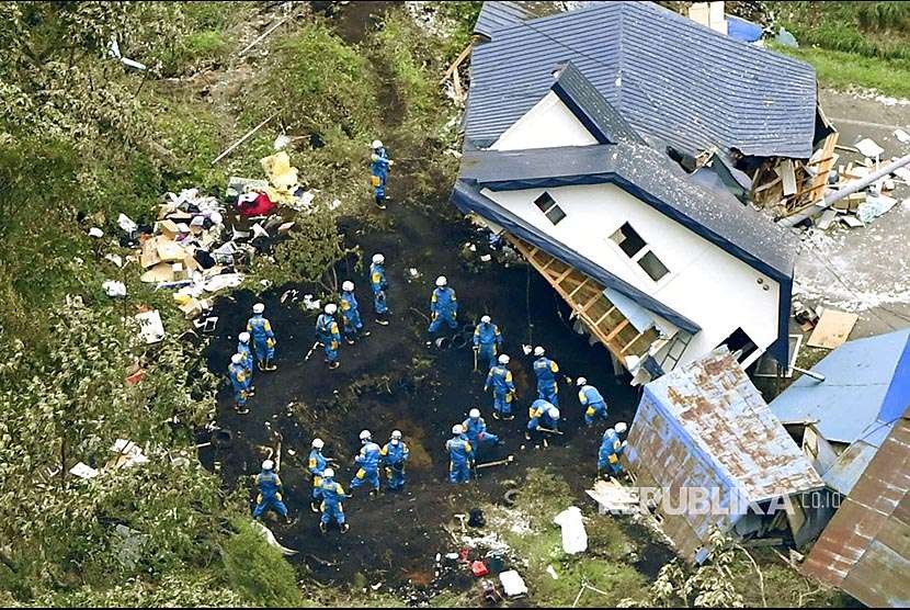 Polisi dan petugas mencari korban di antara rumah warga yang tertimbun longsor Kota Atsuma, Hokkaido, Jepang Selatan, Jumat (7/9). Gempa yang mengguncang bagian paling utara Pulau Hokkaido ini menimbulkan belasan korban jiwa.