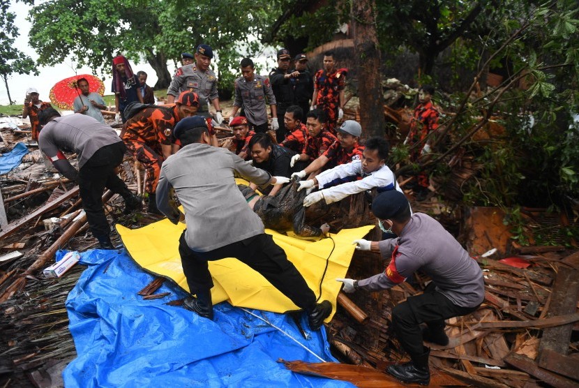 Polisi dan relawan mengevakuasi korban tewas akibat Tsunami yang tertimbun di bawah reruntuhan di kawasan Carita, Banten, Jawa Barat, Senin (24/12/2018)