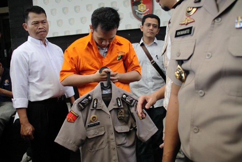 Polisi Gadungan: Petugas menunjukkan tersangka polisi gadungan beserta seragam dan lencana Polisi saat rilis di Polda Metro Jaya, Jakarta, Kamis (25/7). Tersangka berinisial EUW ini beroperasi mengaku sebagai polisi berpangkat brigadir dan bekerja sebagai 