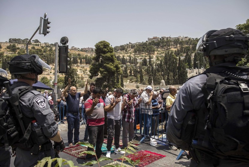 Polisi Israel berjaga-jaga saat warga Palestina beribadah shalat di luar Gerbang Lion di Kota Tua Yerusalem, Jumat (21/7).  