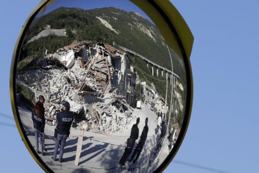 Polisi Italia tampak dari cermin lalu lintas dekat rumah yang hancur akibat gempa bumi di Pescara Del Tronto, Italia, Kamis, 25 Agustus 2016.