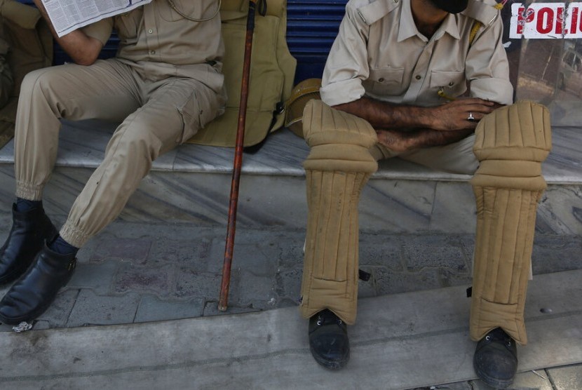 Polisi Kashmir duduk-duduk di depan sebuah toko yang tutup di Srinagar, Kashmir yang dikuasai India, Kamis (22/8).