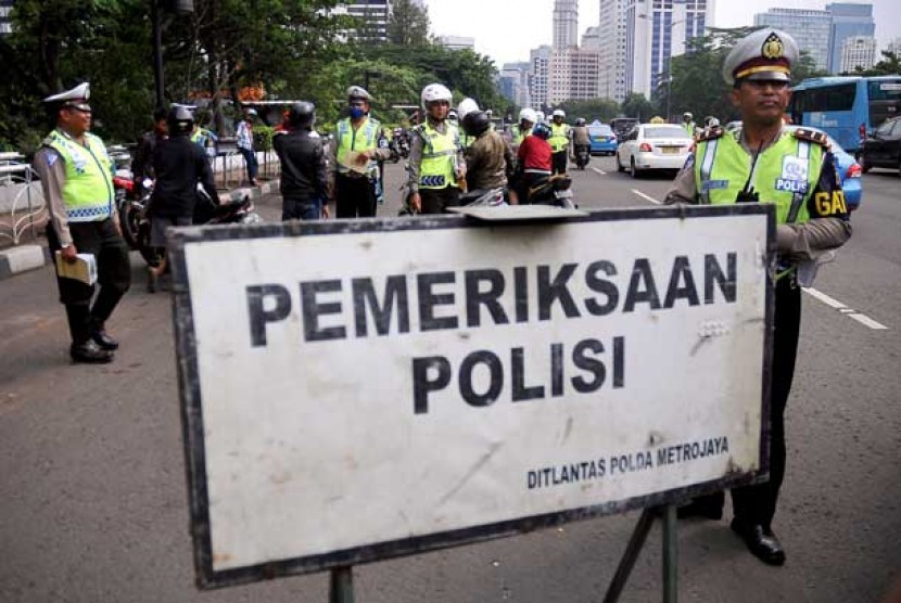 Polisi lalu lintas melakukan tilang terhadap pengendara sepeda motor saat pelaksanaan Operasi Zebra 2013.