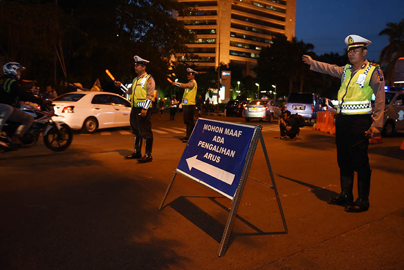 Polisi lalu lintas mengarahkan kendaraan dari Jalan Sudirman ke arah Jalan Galunggung saat penutupan Jalan Thamrin, Jakarta, Kamis (31/12). (Antara/Hafidz Mubarak A.)