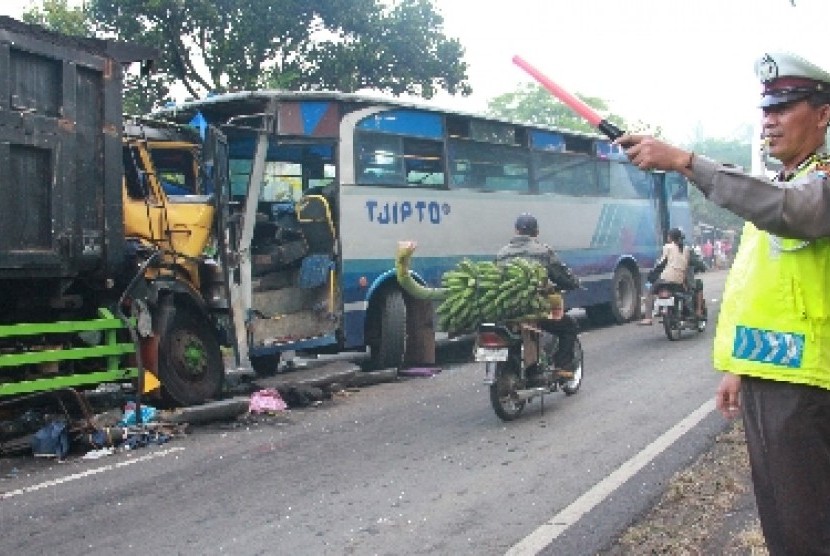 Polisi lalu lintas mengatur jalan di sebelah bus yang terguling.