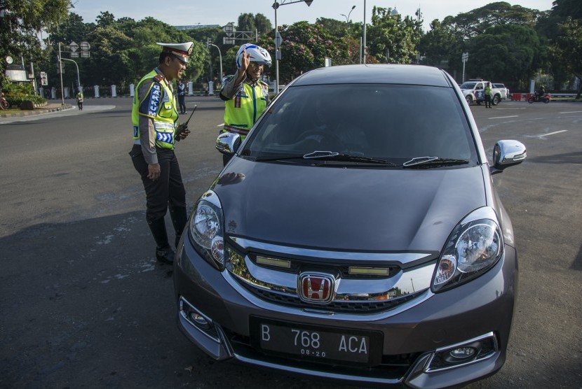 Polisi Lalu Lintas Polda Metro Jaya memberikan imbauan kepada pengendara yang kendaraannya berpelat nomor genap saat uji coba penerapan sistem lalu lintas pelat ganjil-genap di Jalan Medan Merdeka Barat, Jakarta, Rabu (27/7).