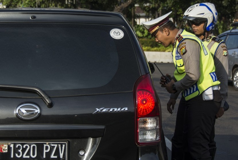Polisi Lalu Lintas Polda Metro Jaya memberikan imbauan kepada pengendara yang kendaraannya berpelat nomor genap saat uji coba penerapan sistem lalu lintas pelat ganjil-genap di Jalan Medan Merdeka Barat, Jakarta, Rabu (27/7). 