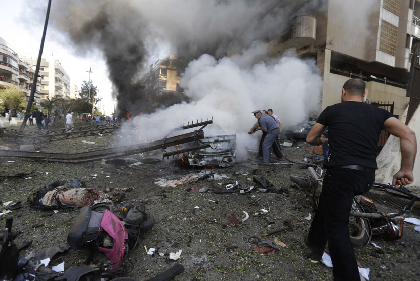  Polisi Lebanon berusaha memadamkan mobil yang terbakar,  akibat ledakan bom dekat Kedutaan Besar Iran  di Beirut, Lebanon, Selasa (19/11).   (AP/Hussein Malla) 