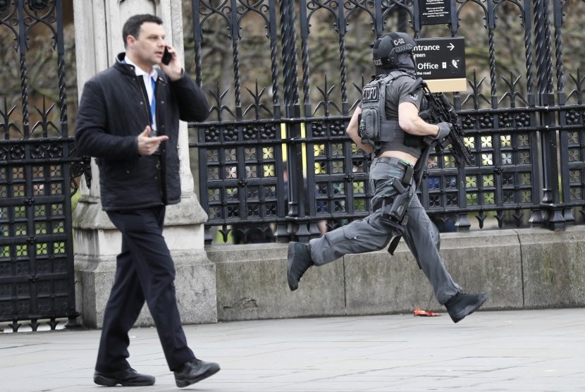 Polisi London bersenjata lengkap berlari di area kompleks Gedung Parlemen  saat insiden penyerangan berlangsung di Jembatan Westminster, London.
