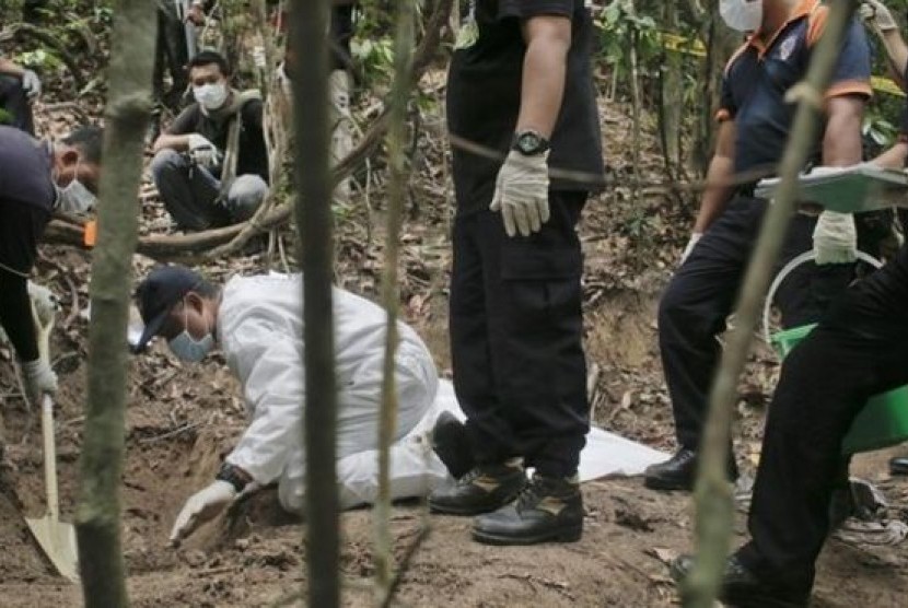 Polisi Malaysia saat menggali kuburan massal yang ditemukan di kamp di perbatasan Malaysia-Thailand, Selasa (26/5). 