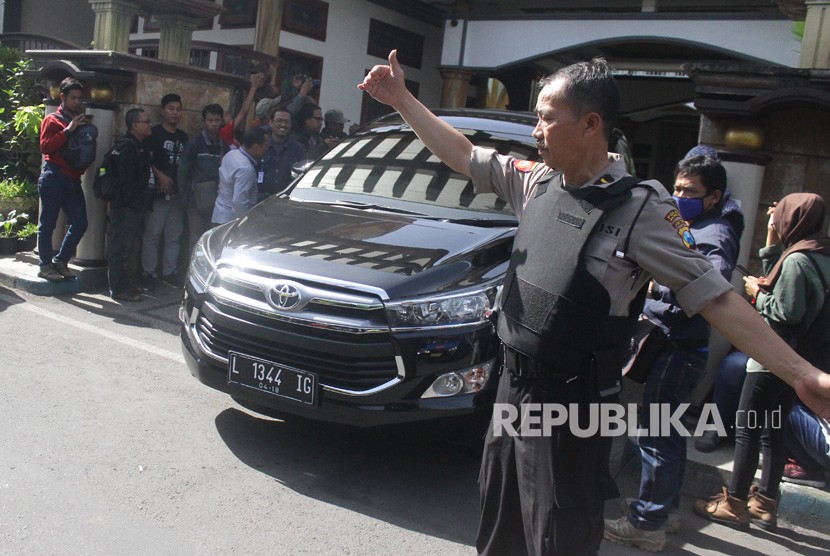 Polisi melakukan pengamanan saat mobil yang ditumpangi para petugas Komisi Pemberantasan Korupsi (KPK) melintas usai melakukan penggeledahan di rumah Walikota Malang, Mochammad Anton di Malang, Jawa Timur, Selasa (20/3).