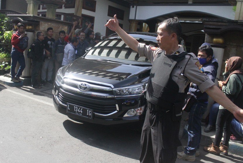 Polisi melakukan pengamanan saat mobil yang ditumpangi para petugas Komisi Pemberantasan Korupsi (KPK) melintas usai melakukan penggeledahan di Kota Malang.