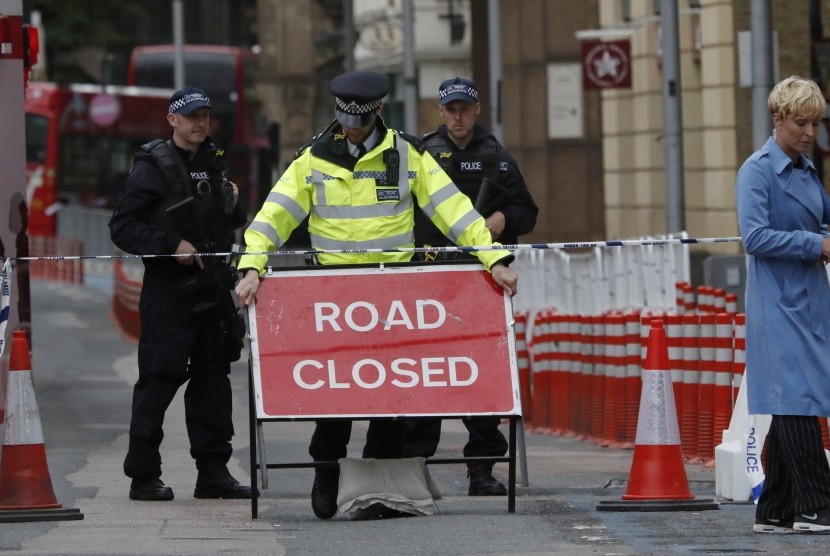 Polisi meletakkan papan yang mengumumkan penutupan jalan terkait insiden teror di Jembatan London dan Pasar Borough, Ahad (4/6).