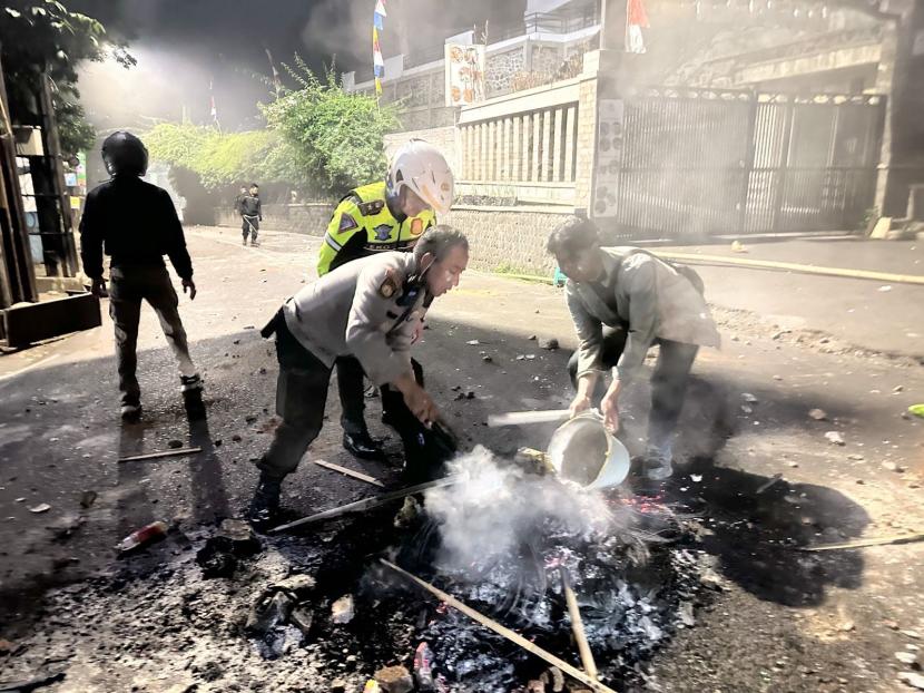 Polisi memadamkan api di Jl Ir H Juanda dalam aksi anarkis Senin (14/8/2023) malam.