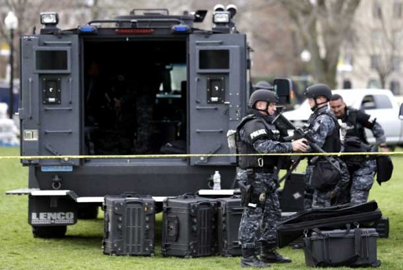 Polisi memakai peralatan senjata taktis pascapeledakan bom yang terjadi di Boston, Selasa (16/4).