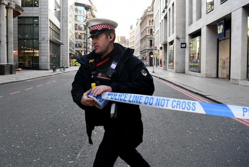 Polisi memasang garis batas polisi di jalan dekat lokasi penusukan di London Bridge, Jumat (29/11).