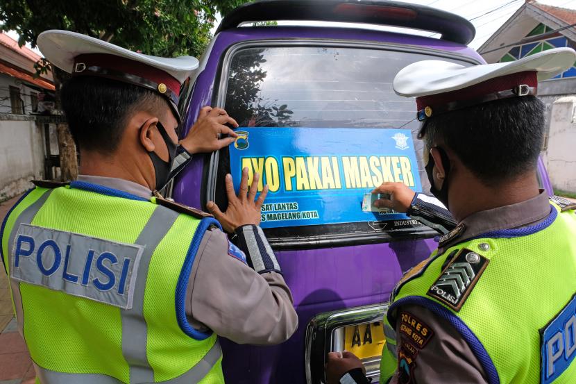 Polisi memasang stiker imbauan memakai masker pada kendaraan angkutan umum di kota Magelang, Jawa Tengah, Jumat (9/10/2020). Guna mencegah penyebaran COVID-19, jajaran Polres Magelang kota gencar melakukan kampanye memakai masker.