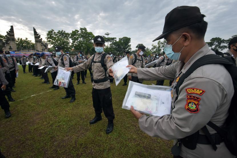 Polisi membagikan alat pelindung diri (APD) kepada personil pengamanan TPS saat apel pergeseran pasukan di Badung, Bali, Selasa (8/12/2020). Pembagian APD berupa masker, antiseptik, sarung tangan karet dan pelindung wajah tersebut untuk penerapan protokol kesehatan COVID-19 saat bertugas mengamankan TPS dalam Pilkada serentak pada 9 Desember 2020.