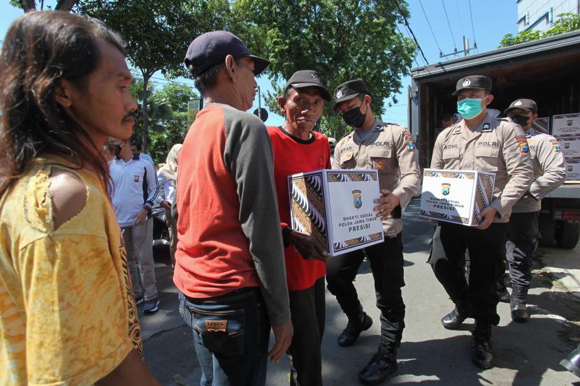 Polisi membagikan bantuan paket sembako kepada sejumlah warga di kawasan Joyoboyo, Kota Surabaya, Jawa Timur, Rabu (14/9/2022).