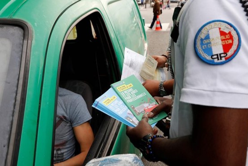 Polisi membagikan brosur pentingnya mengurangi polusi udara kepada pengemudi mobil tua di Paris 