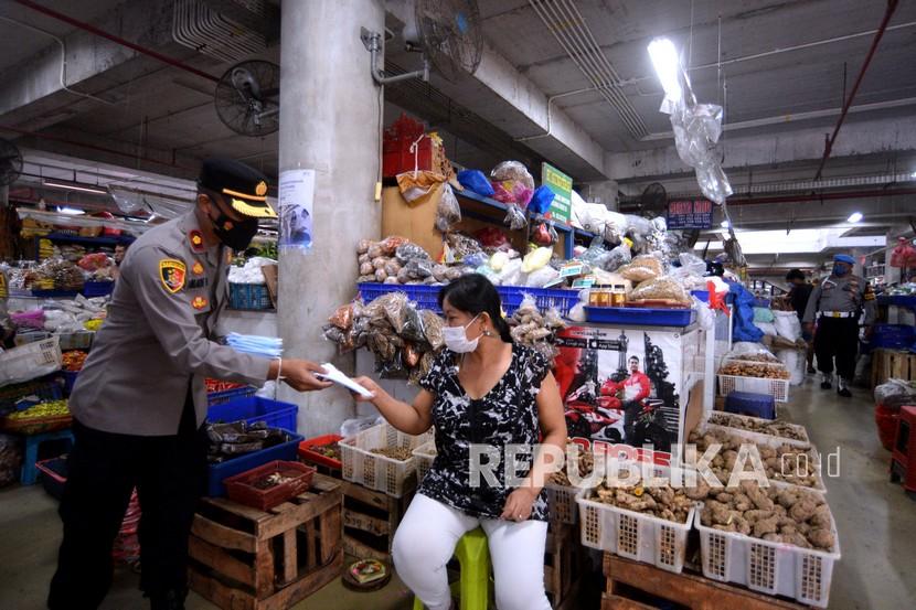 Polisi membagikan masker kepada pedagang pasar saat mengawasi penerapan protokol kesehatan di Pasar Badung, Denpasar, Bali, Jumat (14/1/2022). Kegiatan itu dilakukan untuk memastikan protokol kesehatan tetap diterapkan dengan ketat di pasar tradisional sebagai pencegahan penyebaran COVID-19 khususnya varian Omicron. 