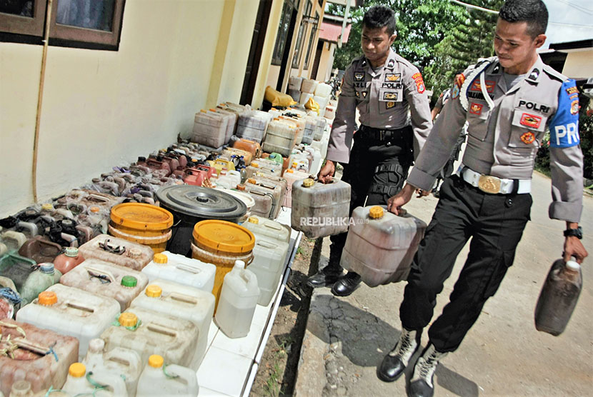 Polisi membawa miras tradisional yang disita dari operasi selama sepekan di Polres Muna, Kabupaten Muna, Sulawesi Tenggara, Selasa (1/5).
