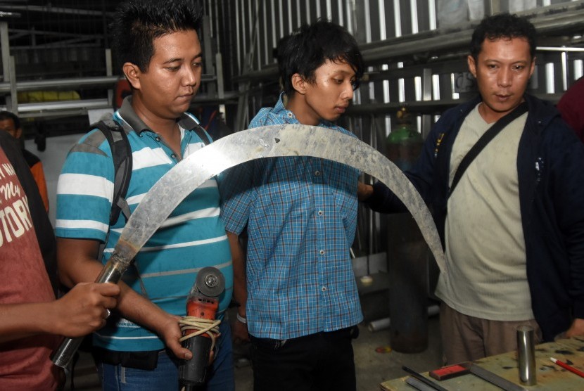 Polisi membawa tersangka anggota geng motor Sanca Bergoyang berinisial KT (kedua kanan) ke tempat pembuatan senjata tajam yang diproduksi kelompok itu di kawasan Tapos, Depok, Jawa Barat, Selasa (6/6) dinihari.