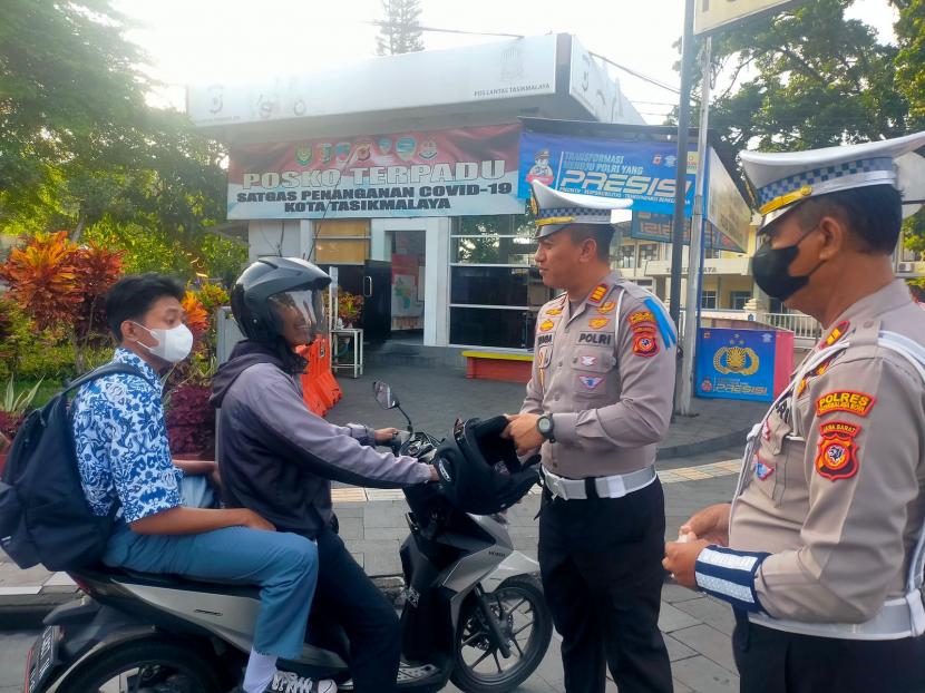Polisi memberikan helm kepada pengendara yang kedapatan tak mengenakannya di Simpang Rancabango, Kota Tasikmalaya, Rabu (12/10/2022). 