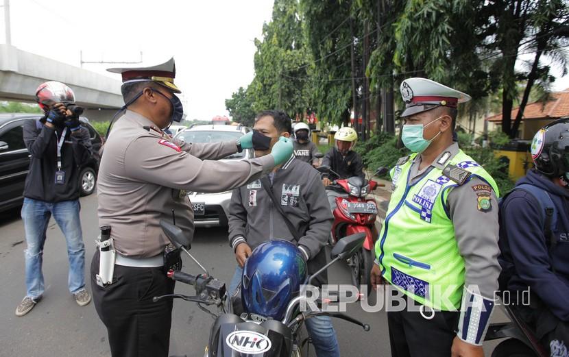 Polisi memberikan masker kepada pengendara sepeda motor saat penerapan Pembatasan Sosial Berskala Besar  (ilustrasi) 