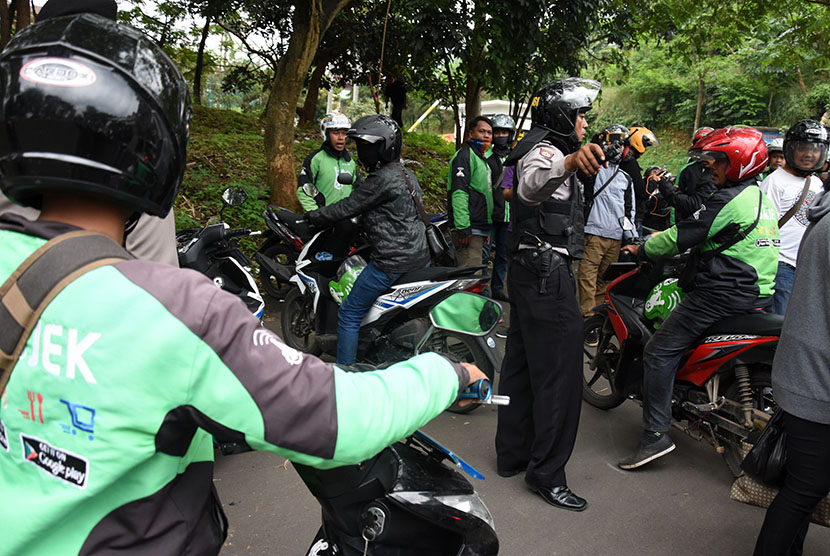 Polisi membubarkan kerumunan pengemudi ojek online untuk mengantisipasi terjadinya gesekan dengan pengemudi angkutan kota (angkot) di Jembatan Panus, Depok, Jawa Barat, Selasa (21/3). 
