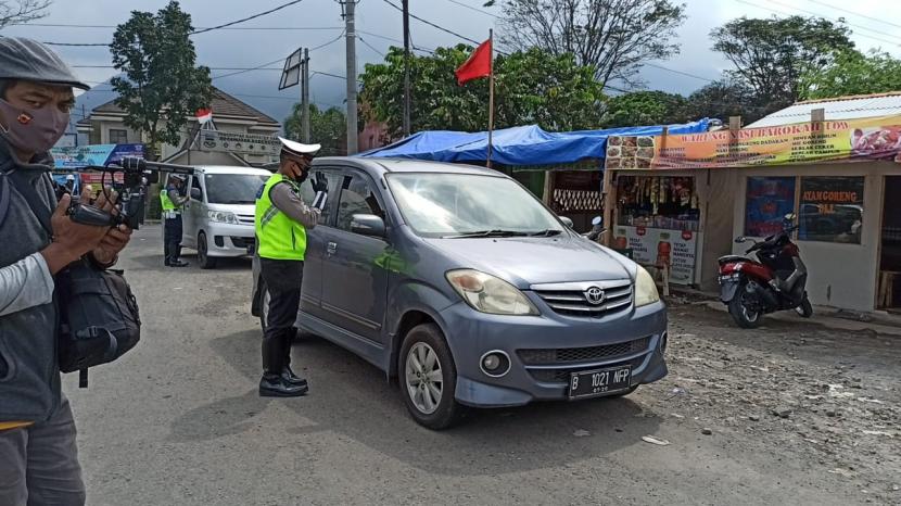 Polisi memeriksa kendaraan yang melintas di wilayah Kabupaten Garut saat pelaksanaaan PSBB.