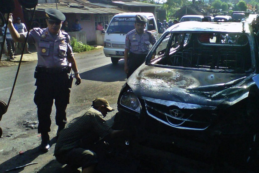 Polisi memeriksa mobil milik anggota Front Pembela Islam (FPI) yang dibakar massa setelah terjadinya bentrok antara FPI dengan warga di Kecamatan Sukorejo, Kendal, Jawa Tengah, Kamis (18/7)