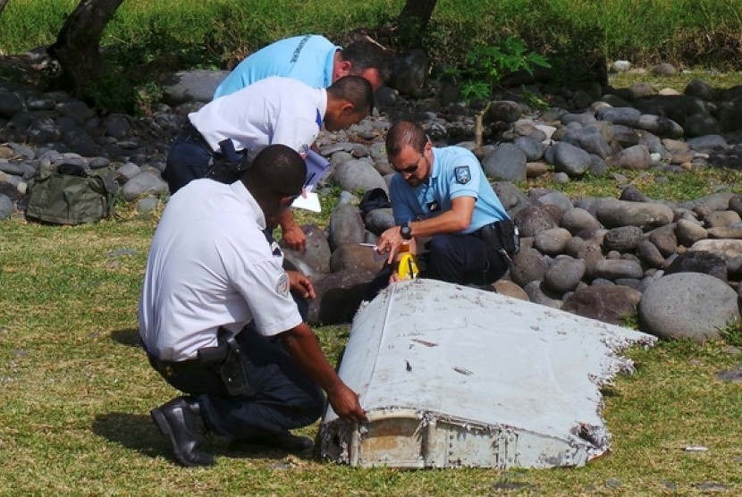  Polisi memeriksa potongan pesawat yang ditemukan di Pantai Saint-Andre, di kepulauan La Reunion di Laut Hindia, (30/7).