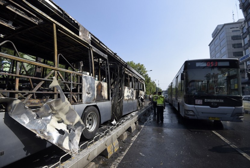 Polisi memeriksa sisa bus Transjakarta yang terbakar di Halte Universitas Indonesia (UI) Salemba, Jakarta, Jumat (3/7). 