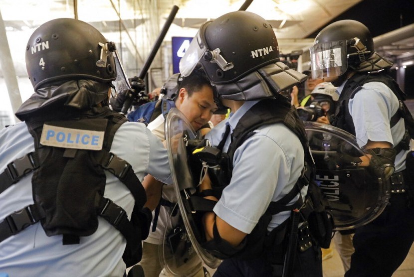 Polisi menahan seorang demonstran di Bandara Internasional Hong Kong, Selasa (13/8).