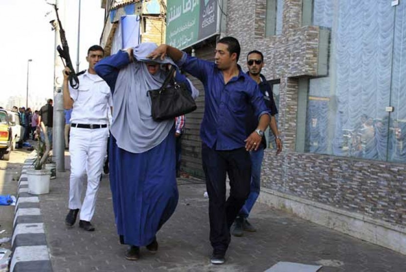  Polisi menahan seorang wanita pengunjuk rasa pendukung Presiden Mursi di Alexandria, Jumat (1/11).
