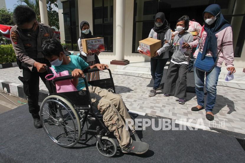 Polisi mendorong kursi roda penyandang disabilitas yang telah divaksin COVID-19 