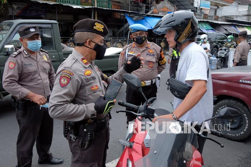 Polisi menegur warga negara asing (WNA) yang tidak mengenakan masker saat razia masker di Denpasar, Bali, Sabtu (5/2/2022). Razia masker dilakukan untuk mendisiplinkan masyarakat dalam menerapkan protokol kesehatan khususnya penggunaan masker yang benar sebagai upaya mencegah penyebaran COVID-19 menyusul terjadinya lonjakan kasus COVID-19 di Bali. 