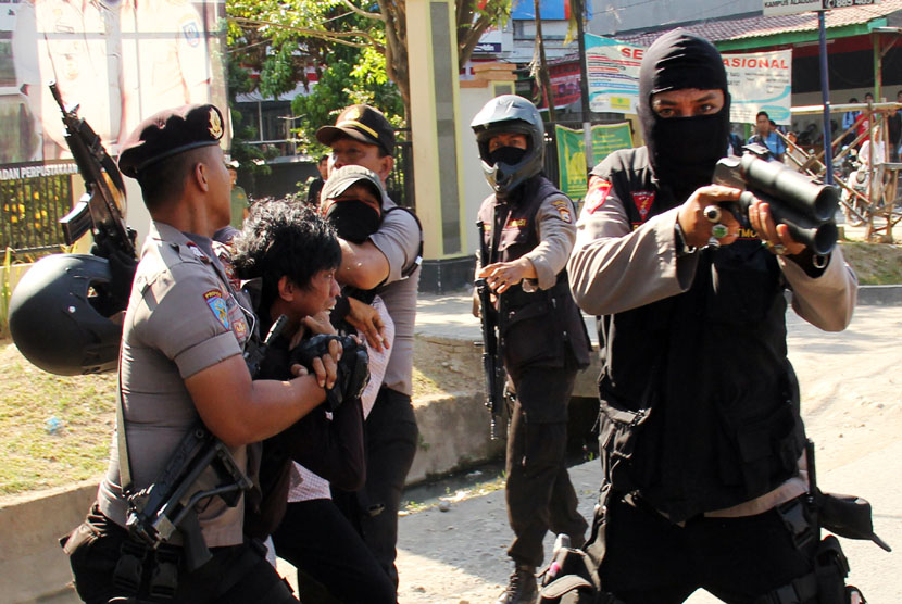   Polisi mengamankan dua mahasiswa saat terjadi bentrokan antara polisi dan mahasiswa di depan Kampus Universitas Muhammadiyah (Unismuh) Makassar, Sulsel, Senin (15/9). (Antara/Yusran Uccang)