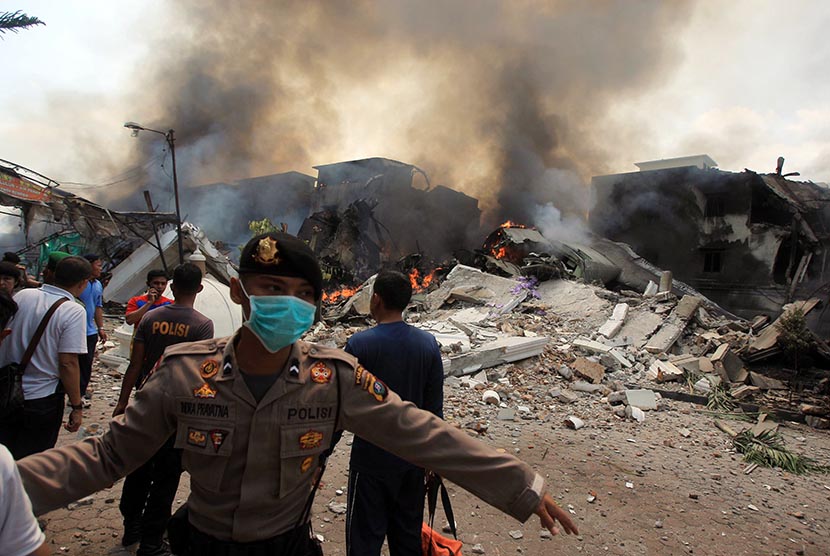  Polisi mengamankan lokasi jatuhnya pesawat Hercules C-130 TNI AU di Medan, Selasa (30/6). (EPA/Dedi Sahputra)