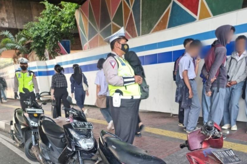 Polisi mengamankan sejumlah pelajar yang berkonvoi dengan membawa senjata tajam di lampu merah Grogol, Jakarta Barat, Selasa (12/9/2023). 