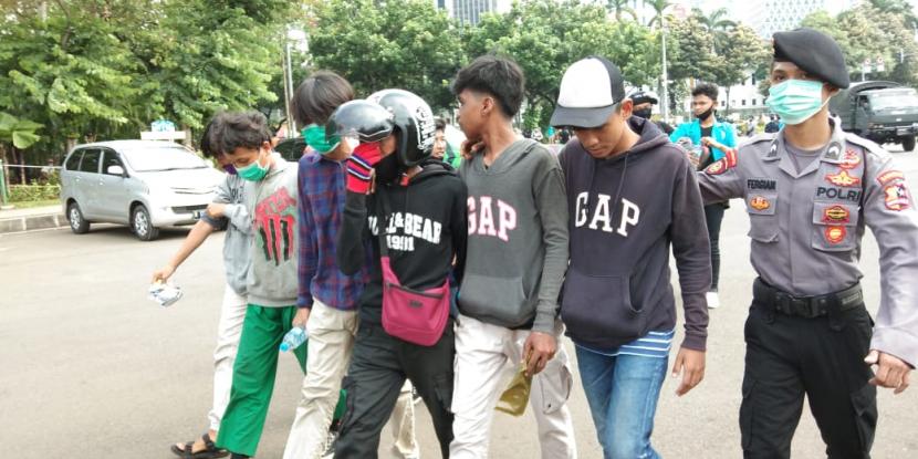 Polisi mengamankan sejumlah remaja yang hendak bergabung dengan massa mahasiswa dan buruh di sekitar Patung Kuda, Jakarta Pusat, Selasa (20/10). 