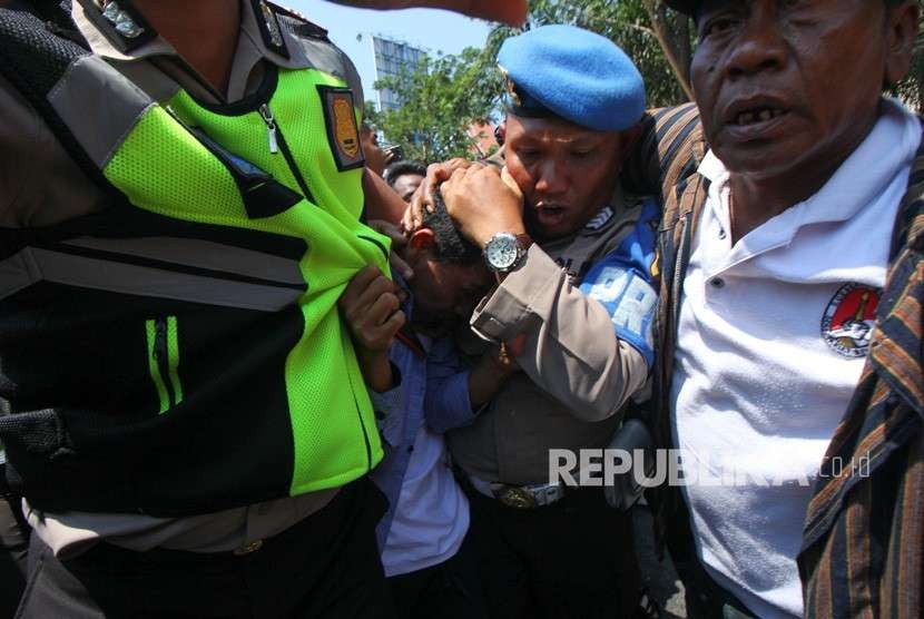 Polisi mengamankan seorang pemuda dari amukan massa saat aksi yang melibatkan dua kubu yang mendeklarasikan #2019 Ganti Presiden dan kubu yang menentang dan menyerukan cinta NKRI, di Jalan Indrapura, Surabaya, Jawa Timur, Ahad (26/8).