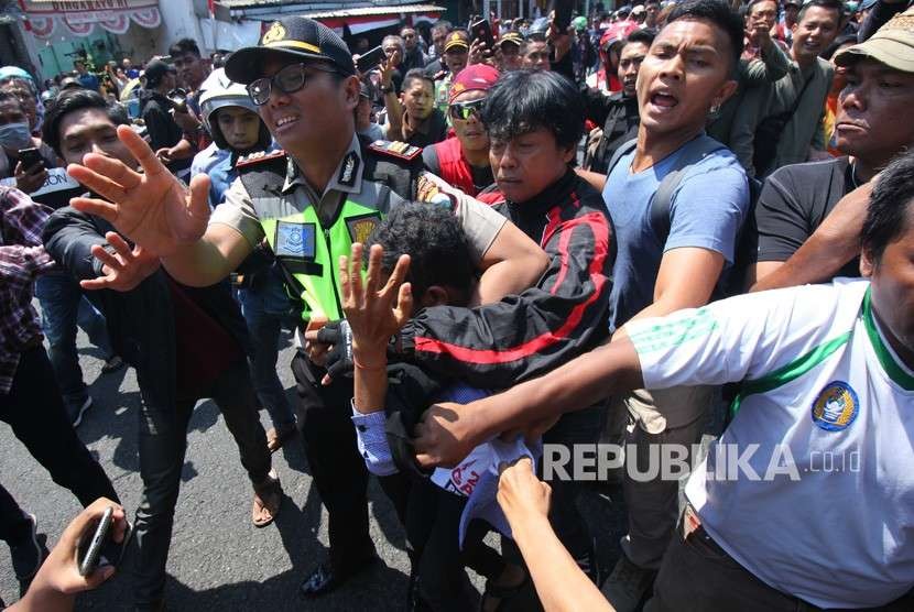 Polisi mengamankan seorang pemuda dari amukan massa saat aksi yang melibatkan dua kubu yang mendeklarasikan #2019 Ganti Presiden dan kubu yang menentang dan menyerukan cinta NKRI, di Jalan Indrapura, Surabaya, Jawa Timur, Ahad (26/8).