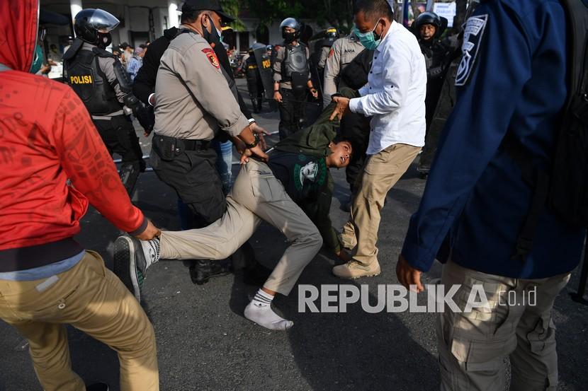 Polisi mengamankan seorang pengunjuk rasa saat unjuk rasa menolak Undang-undang Cipta Kerja di depan Gedung Negara Grahadi, Surabaya, Jawa Timur, Kamis (8/10/2020). Aksi yang dikuti ribuan orang dari berbagai elemen mahasiswa dan buruh tersebut berakhir ricuh dan mengakibatkan sejumlah fasilitas umum rusak. 