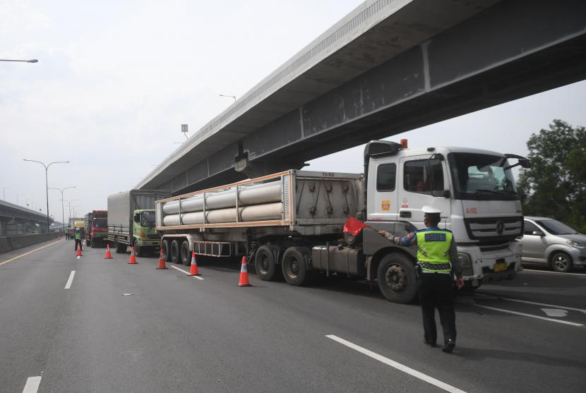 Polisi mengarahkan angkutan barang untuk keluar dari Tol Jakarta-Cikampek melalui pintu tol Karawang Barat di Karawang, Jawa Barat, Rabu (23/12/2020).