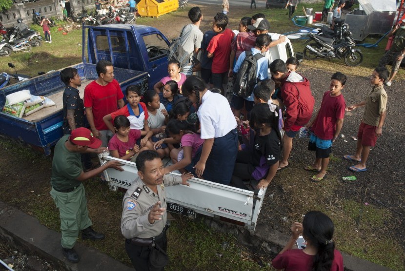 Polisi mengatur anak-anak pengungsi Gunung Agung yang berangkat ke sekolah sementara untuk mengisi waktu mereka selama di penampungan di Desa Manggis, Karangasem, Bali, Selasa (26/9). 