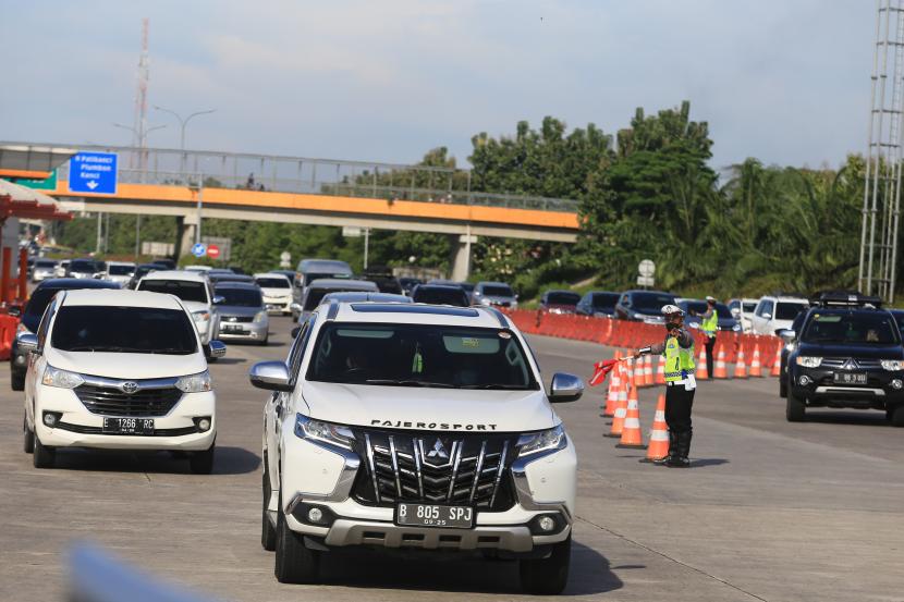 Polisi mengatur arus kendaraan saat penerapan jalur satu arah di gerbang Tol Cipali, Palimanan, Cirebon, Jawa Barat, Jumat (23/12/2022).